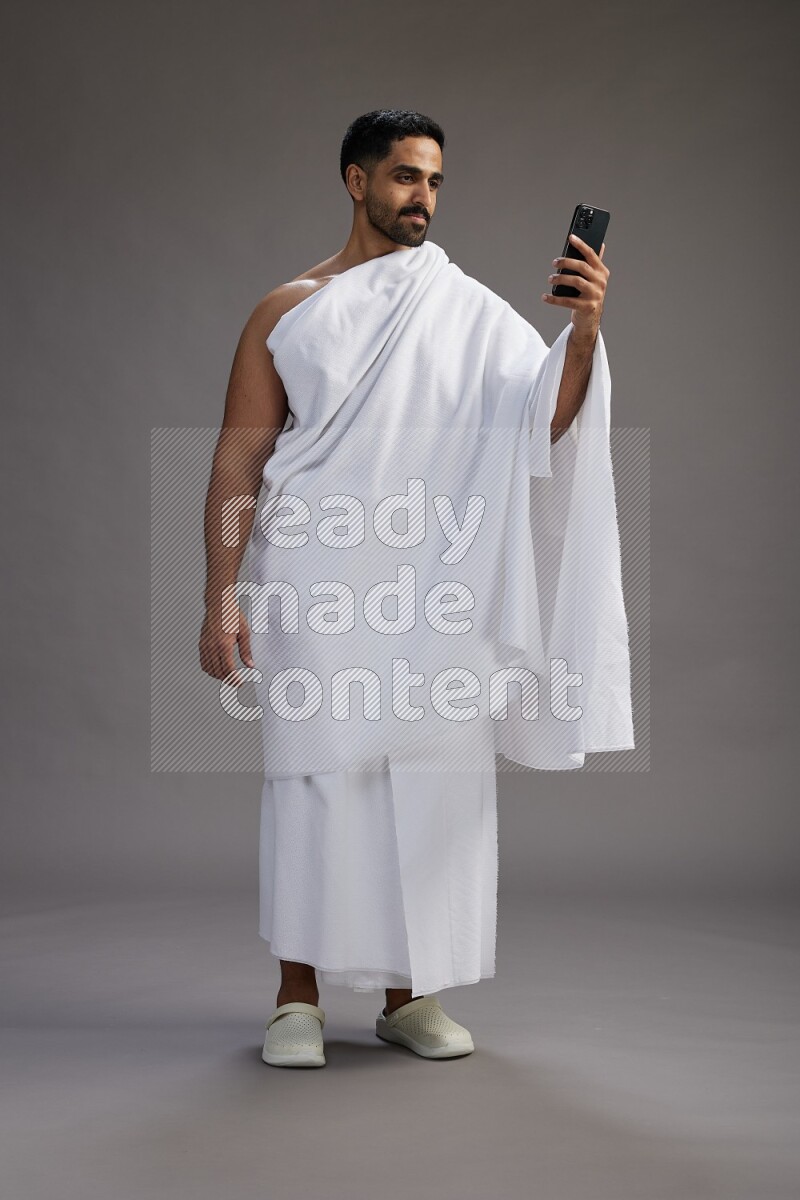 A man wearing Ehram Standing taking selfie on gray background