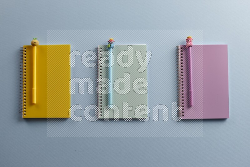 Multicolored notebooks with different school supplies on blue background