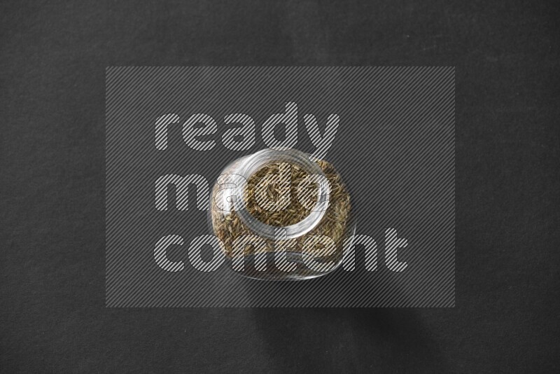 كمون في وعاء زجاجي علي خلفية سوداء