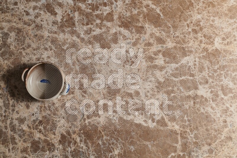 A multicolored pottery bowl on beige marble background