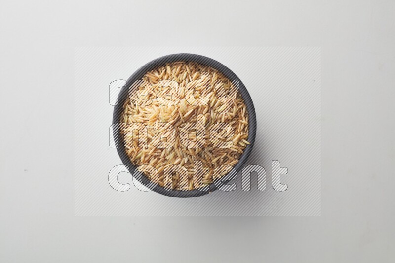 Top-view shot of long grain brown rice in a container on white background