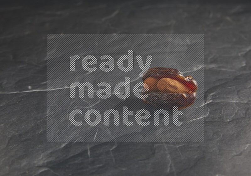 almond stuffed madjoul date on a black textured background
