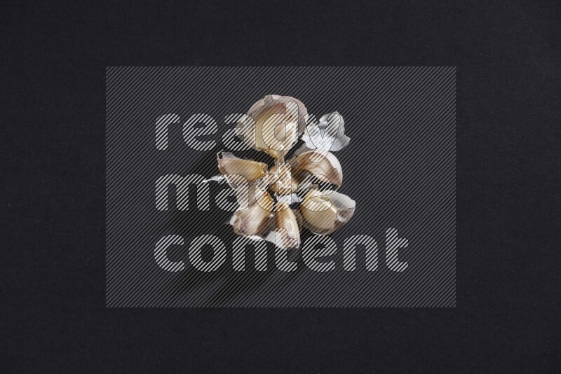 رأس ثوم مشقوقة تظهر الفصوص بداخلها على خلفية سوداء