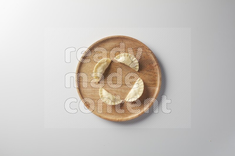 Four Sambosas on a wooden round plate on a white background