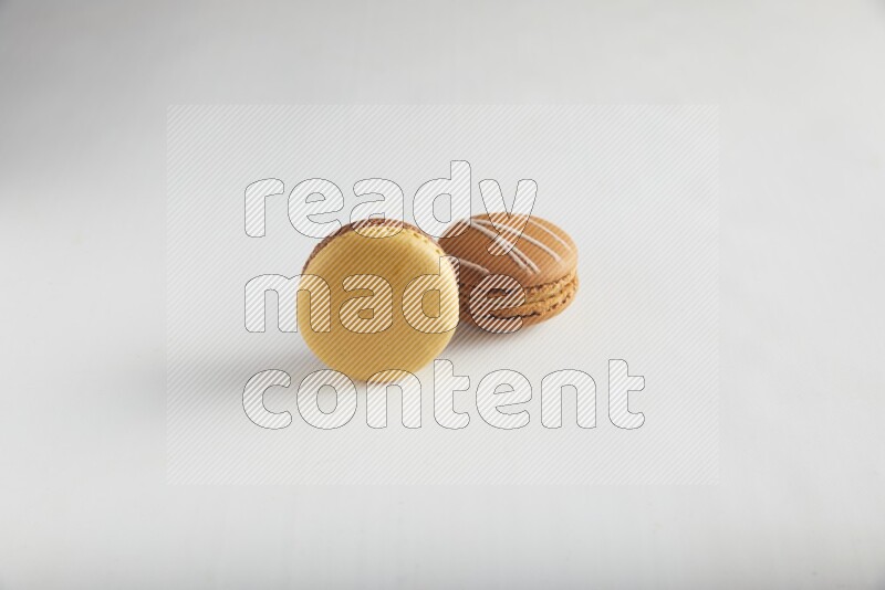 45º Shot of of two assorted Brown Irish Cream, and Yellow, and Brown Chai Latte macarons on white background