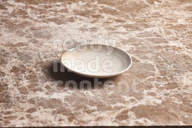 A beige pottery plate on beige marble background