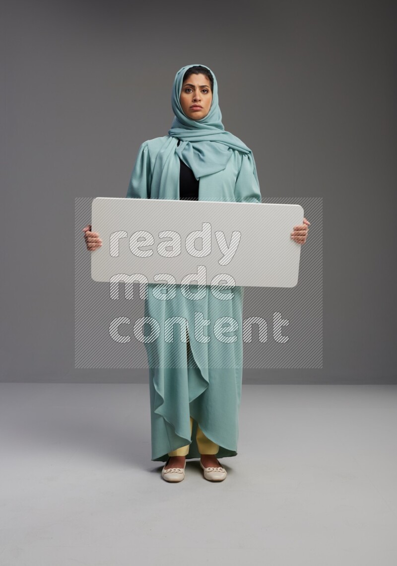 Saudi Woman wearing Abaya standing holding board on Gray background