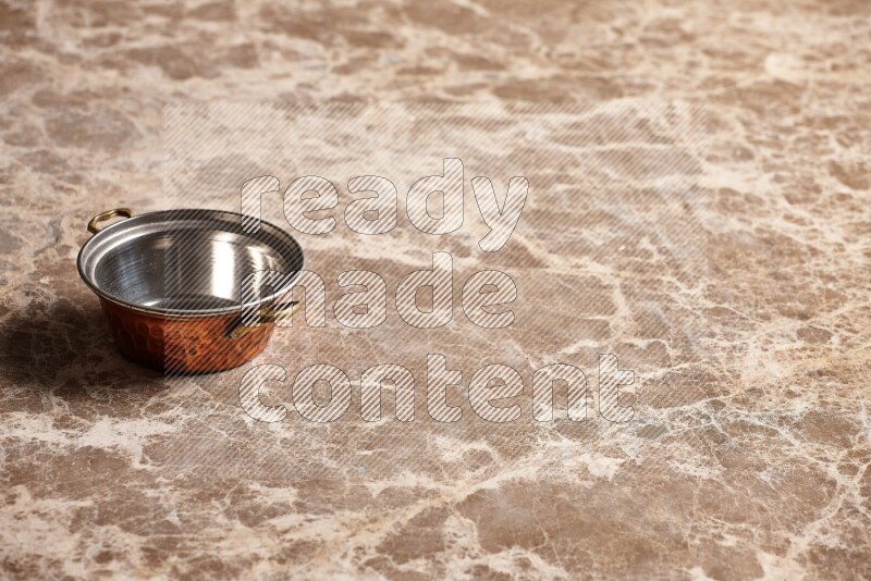 A small copper pot on beige marble background