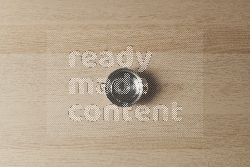 A small copper pot on light wooden background
