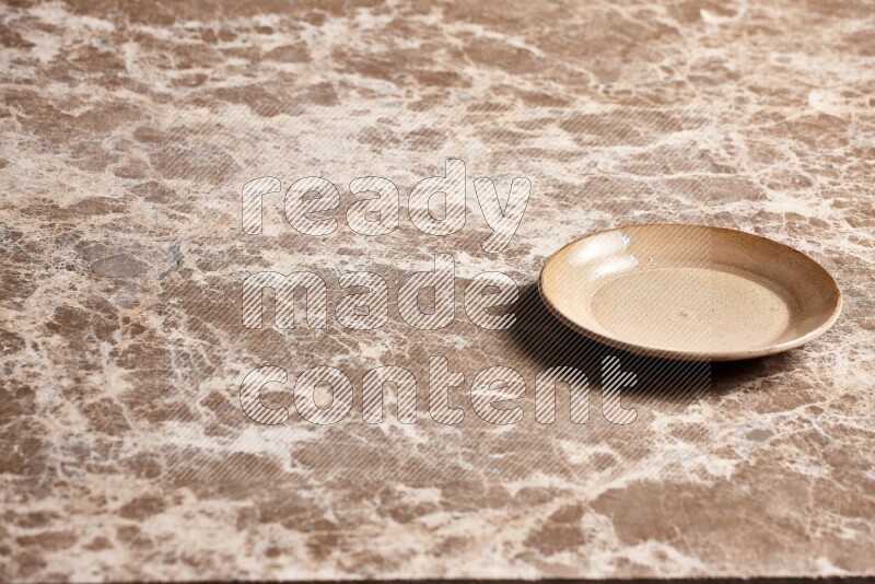A beige pottery plate on beige marble background