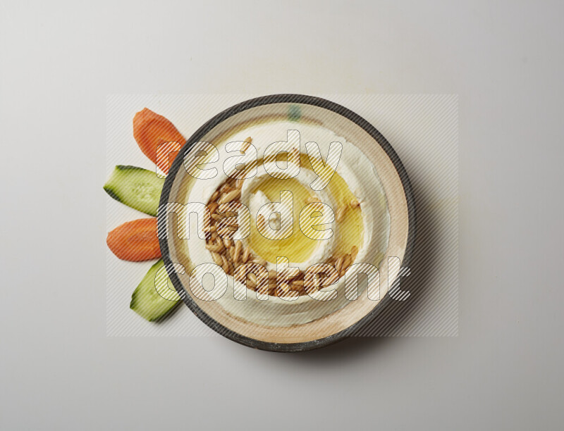 Lebnah garnished with pine nuts in a pottery plate on a white background