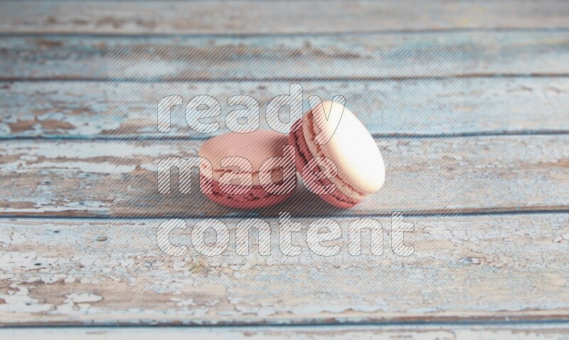45º Shot of two Pink Litchi Raspberry macarons on light blue wooden background