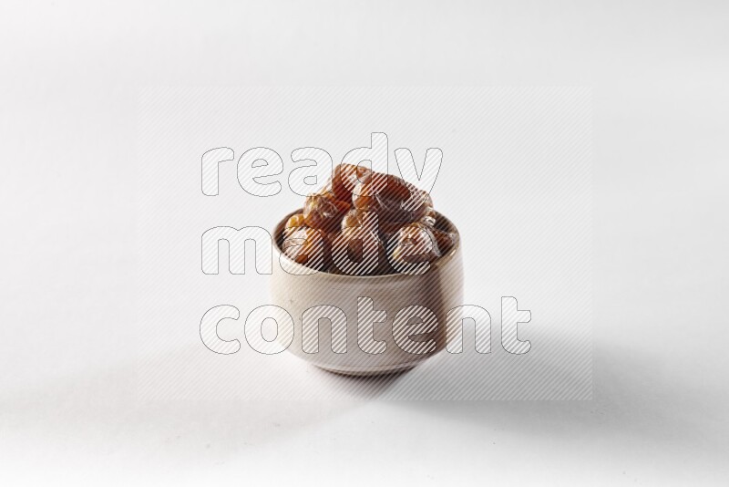 Dates in a beige pottery bowl on white background