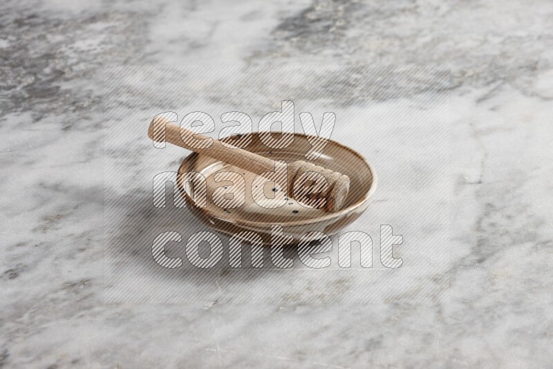 Multicolored pottery plate with wooden honey dipper in it on grey marble background