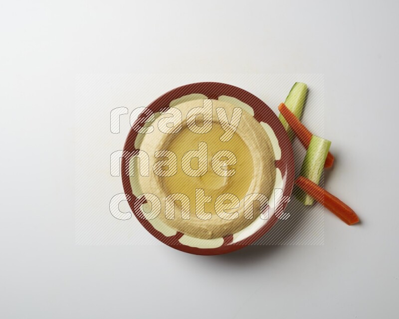 Hummus in a traditional plate garnished with olive oil on a white background