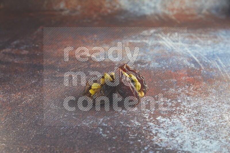 two pistachio stuffed madjoul dates on a rustic reddish background