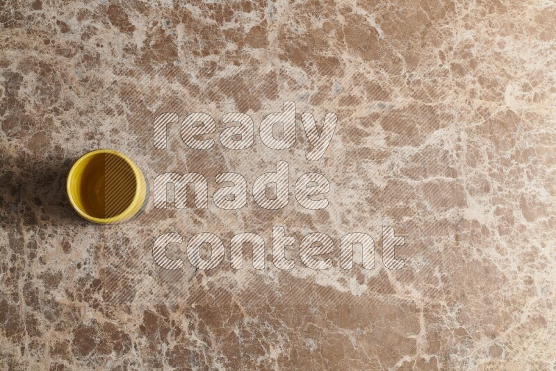A multicolored pottery cup on beige marble background