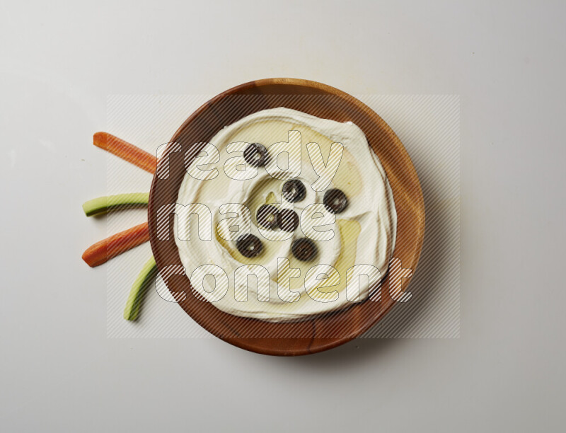 Lebnah garnished with sliced olives in a wooden plate on a white background
