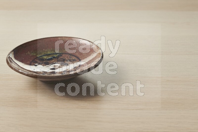 A decorative pottery plate on light wooden background