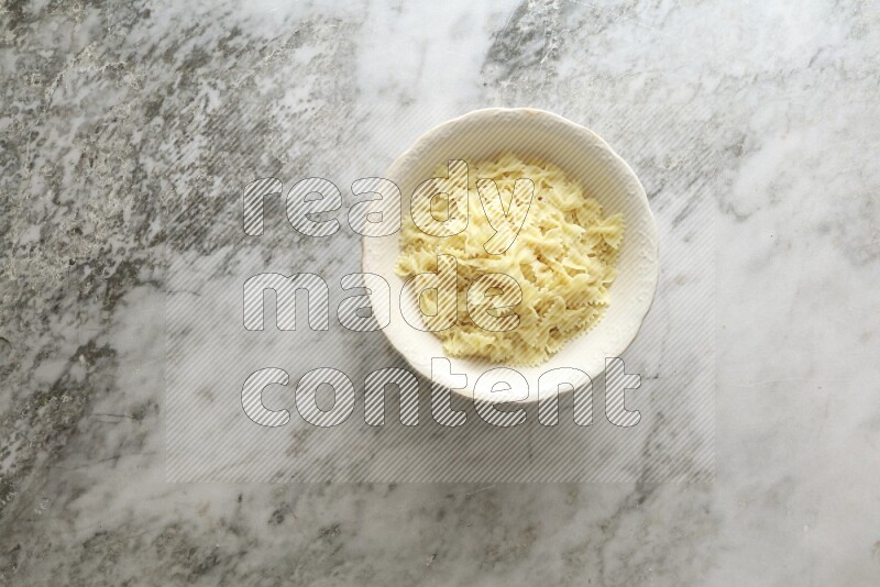 White bowl full of pasta on grey marble background