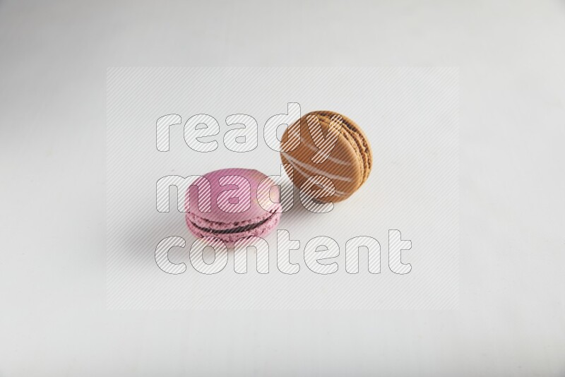45º Shot of of two assorted Brown Irish Cream, and Purple Strawberry macarons on white background
