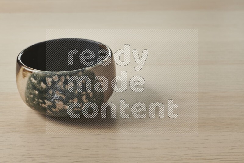 A multicolored pottery bowl on light wooden background
