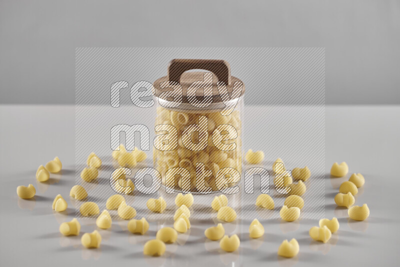 Raw pasta in a glass jar on light grey background