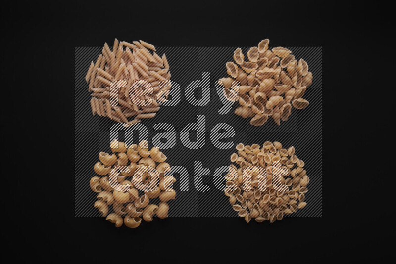 Different pasta types in bunches on black background