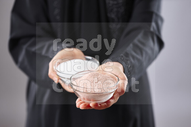 Woman in abaya holding different kinds of spices in different positions