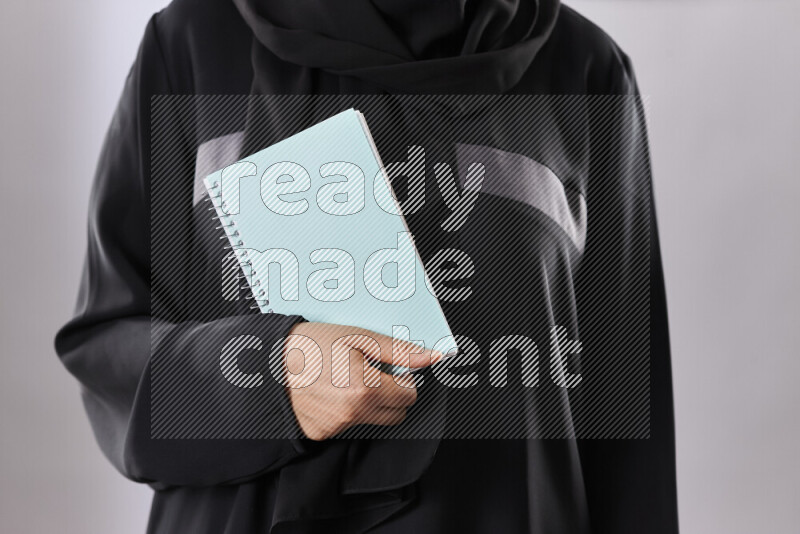 A woman in abaya holding books and a board in different positions (back to school)
