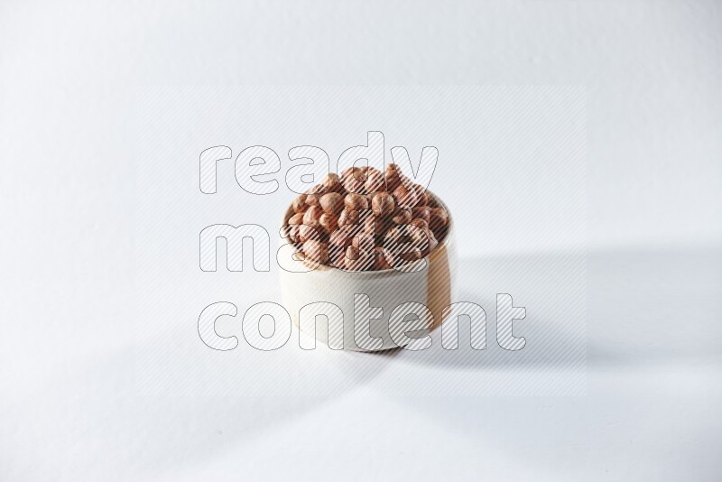 A beige ceramic bowl full of peeled hazelnuts on a white background in different angles