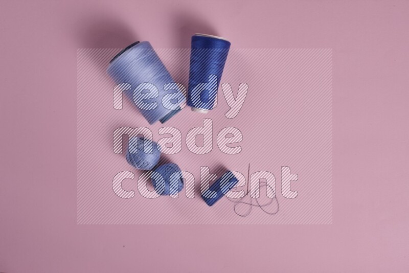 A blue collection of sewing and tailoring tools arranged on a pink background