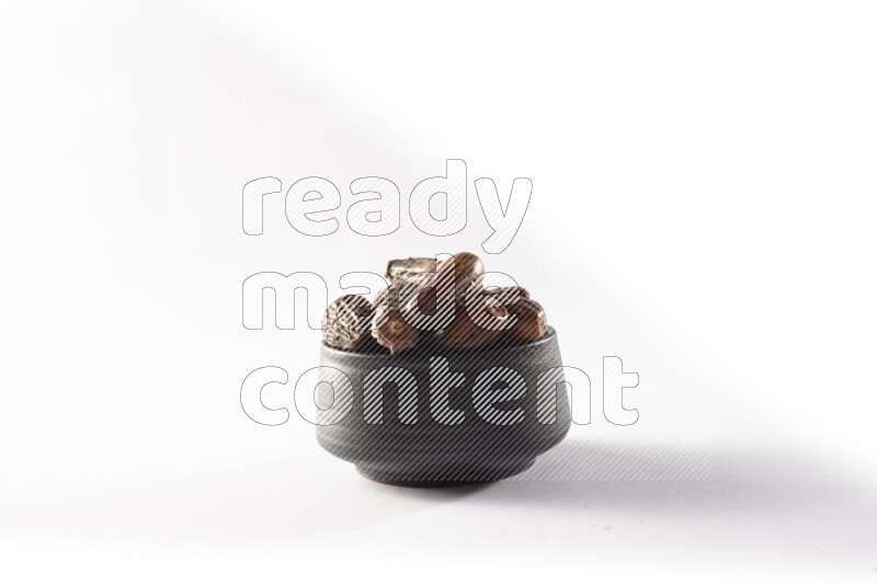 Dates in a black pottery bowl on white background