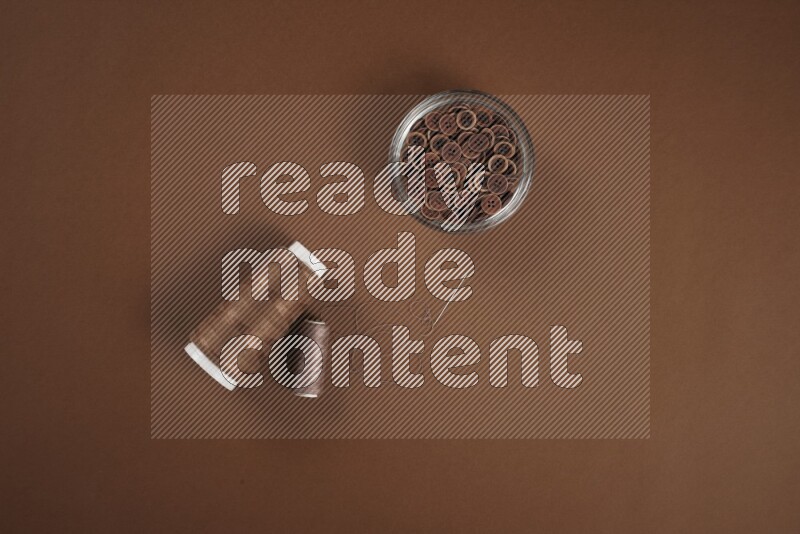 A brown collection of sewing and tailoring tools arranged on a brown background
