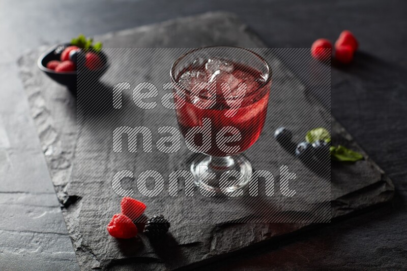 A glass of mixed berries juice on black background