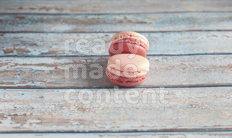 45º Shot of two Pink Litchi Raspberry macarons on light blue wooden background