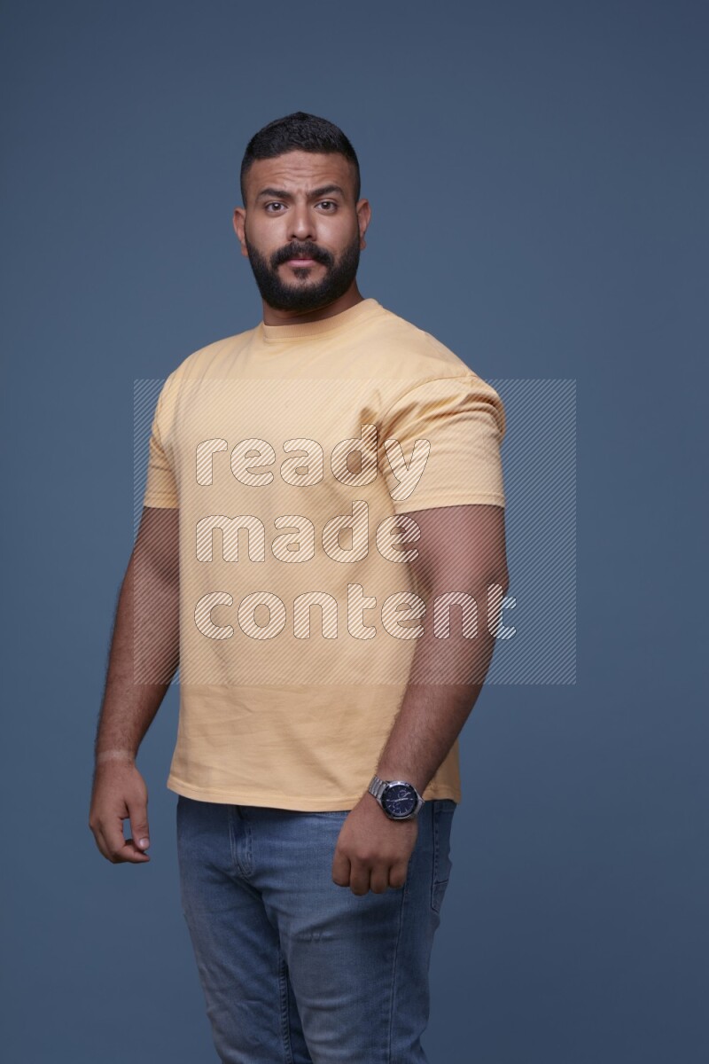 رجل يرتدي قميص اصفر بأكمام قصيرة وبنطال جينز ازرق يقف بأوضاع مختلفة