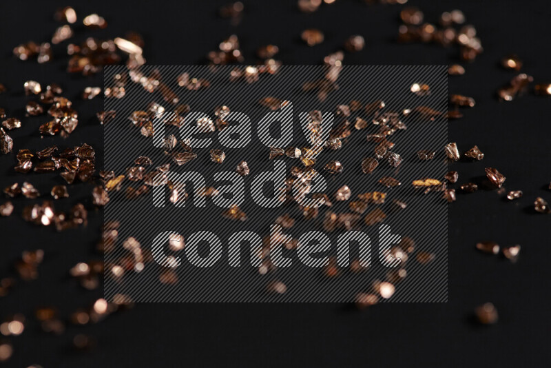 Bronze shimmering fragments of glass scattered on a black background