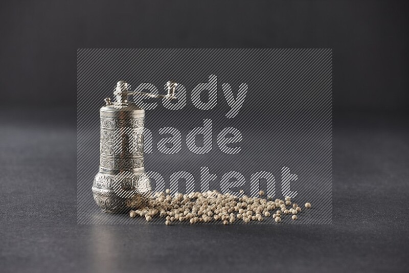 White pepper with a metal pepper grinder on black flooring