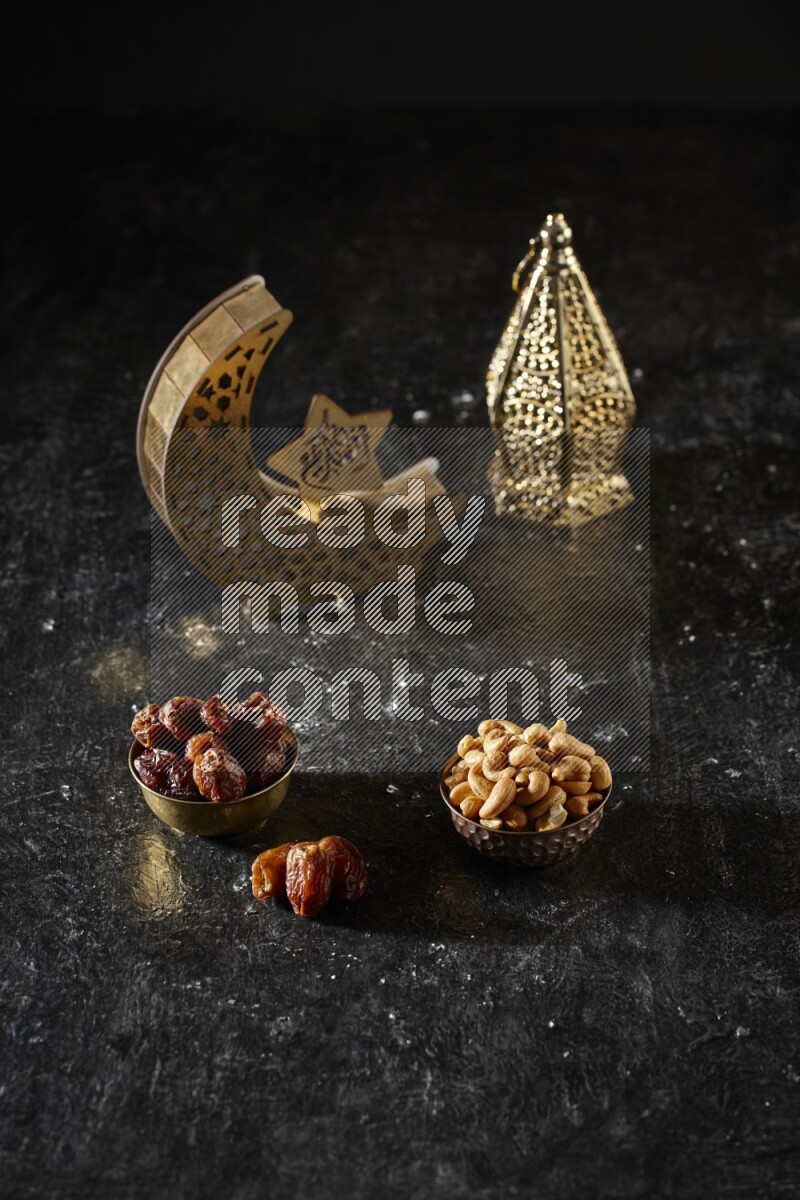 Dates in a metal bowl with cashews beside golden lanterns in a dark setup