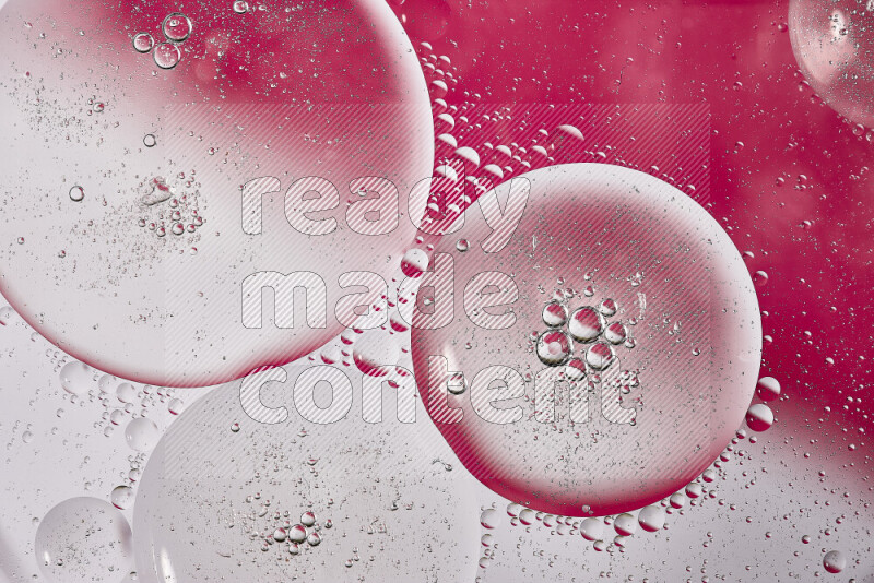 Close-ups of abstract oil bubbles on water surface in shades of white and pink