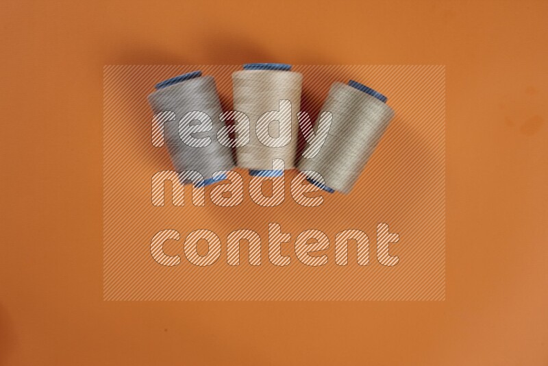 مجموعة من أدوات الخياطة والتفصيل بنية اللون على خلفية برتقالية