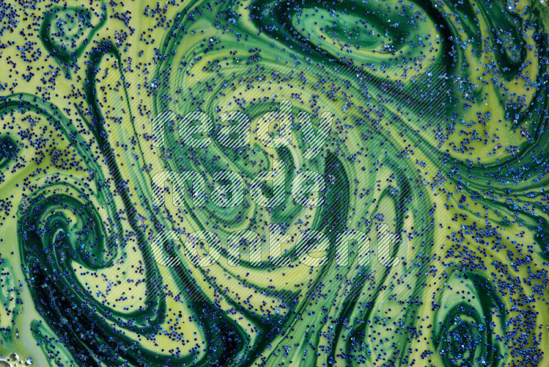 A close-up of sparkling blue glitter scattered on swirling blue and green background