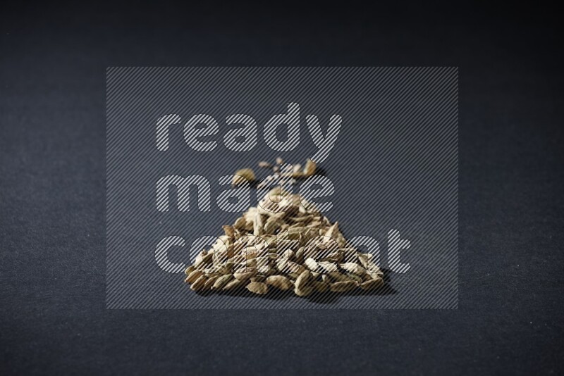Cardamom in a triangle shape on black flooring