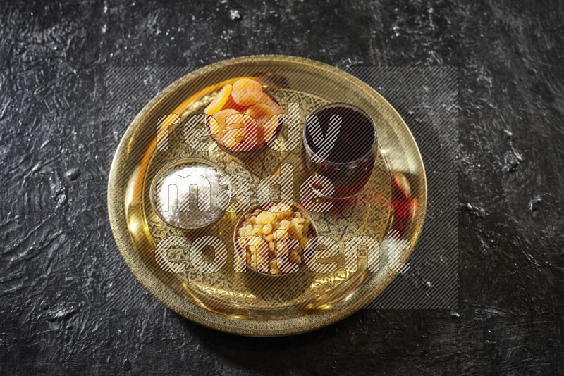 Dried fruits in metal bowls with Hibiscus on a tray in dark setup