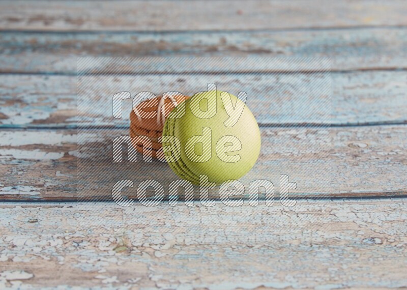 45º Shot of of two assorted Brown Irish Cream, and Green Pistachio macarons  on light blue background