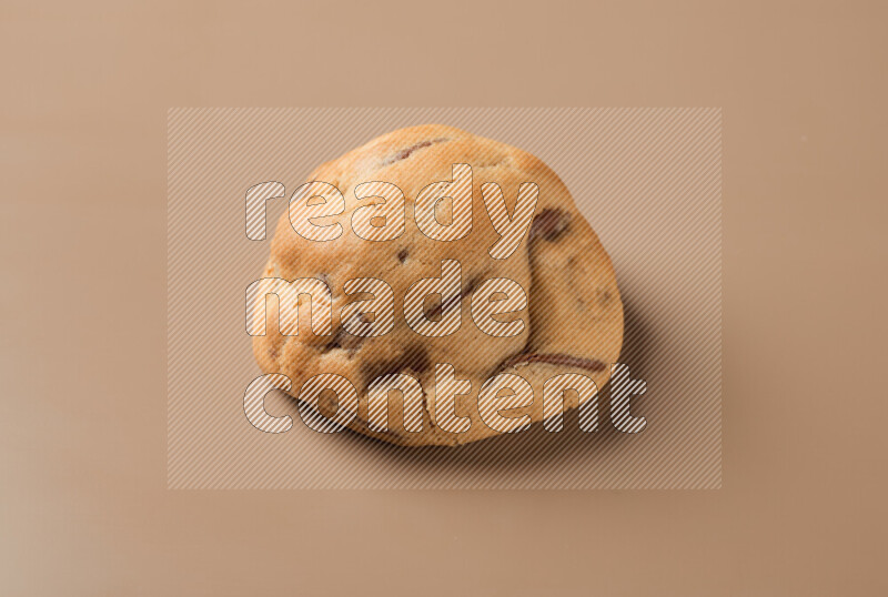 a whole chocolate chip cookie on a brown background