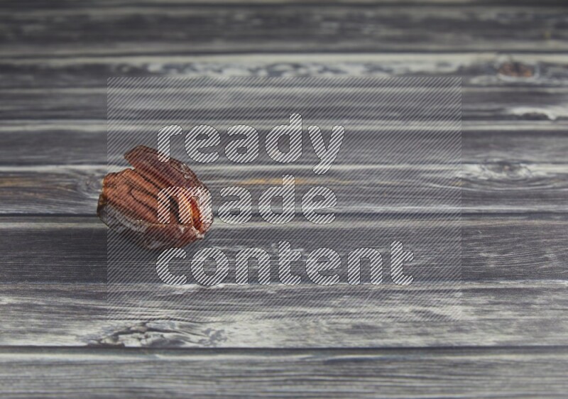pecan stuffed madjoul date on a wooden grey background