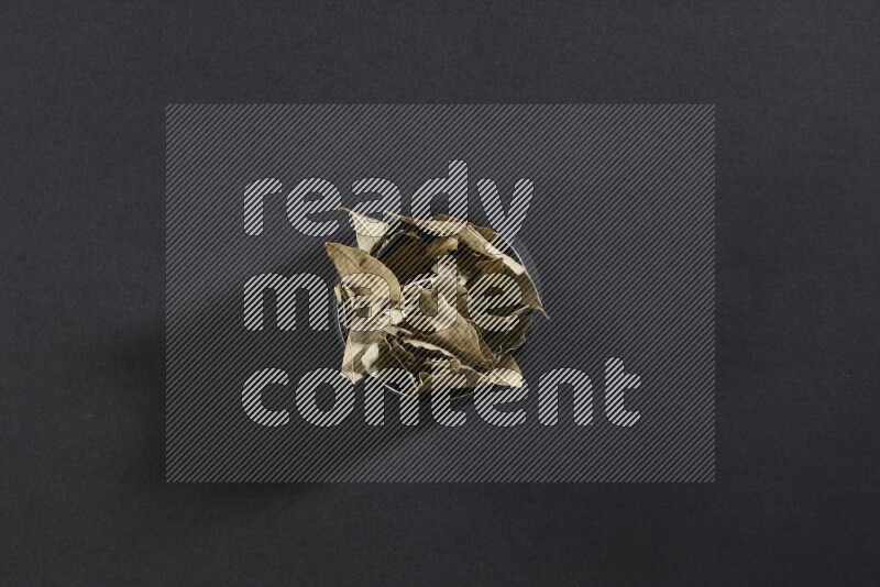 وعاء فخاري أسود ممتلئ بأوراق الغار المجففة على أرضية سوداء