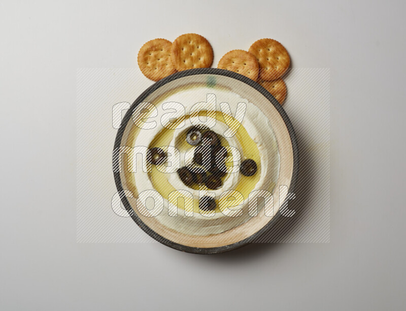 Lebnah garnished with sliced olives in a pottery plate on a white background